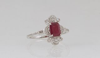 Lady's Platinum Dinner Ring, with a rectangular 1.23 ct. ruby, atop a floriform border of round diamonds and demilune diamond mounted lugs, the should