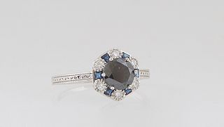 Lady's Platinum Dinner Ring, with a circular .99 ct. round black diamond, atop a border of princess cut blue sapphires alternating with round diamonds