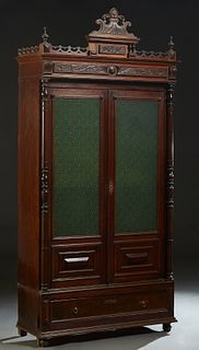 French Provincial Carved Walnut Bookcase, c. 1870, the ornate stepped pierced crown over setback double green glass doors, flanked by turned pilasters
