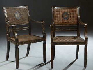 Pair of Italian Ebonized Caned Fauteuils, late 19th c., with gilt and painted floral decoration, the canted curved caned backs to scrolled arms, on tr