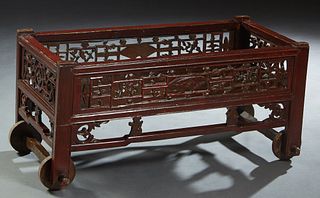 Chinese Red Lacquered Rolling Cart, 20th c., the pierced sides with floral and fan decoration, on thick wooden wheels, H.- 19 1/2 in., W.- 44 in., D.-