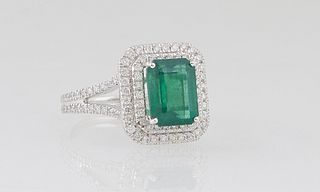 Lady's Platinum Dinner Ring, with a 2.65 ct. emerald atop a double concentric graduated border of round diamonds, the split shoulders of the band moun