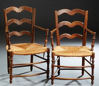 Pair of French Provincial Carved Beech Rush Seat Armchairs, early 20th c., the arched ladderbacks over chamfered arms, to a bowfront rush seat, on tur