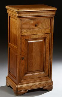 French Louis Philippe Carved Oak Confiturier, 19th c., the stepped rounded edge and corner top over a frieze drawer and a long fielded panel cupboard 