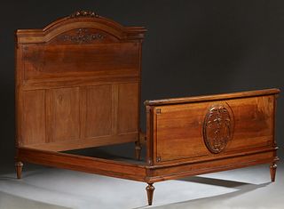 French Louis XVI Style Carved Walnut Double Bed, early 20th c., the arched floral carved headboard joined by wooden rails and a fielded panel footboar