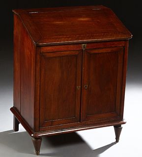 French Louis Philippe Carved Mahogany Slant Top Desk, 19th c., the lift top lid over open storage and double cupboard doors, on a plinth base on turne
