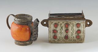 Two Moroccan Pieces, 20th c., consisting of a stamped metal Qur'an holder pendant, with incised decoration, one side mounted with 9 red stones, design