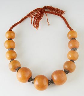 Moroccan Berber Amber Resin Necklace, 20th c., with eleven large graduated beads, with metal spacers, on a twisted wool cord, L.- 18 in.