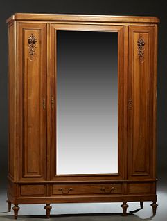 French Louis XVI Style Carved Walnut Armoire, c. 1900, the stepped rounded corner crown over a central wide beveled mirror door above a lower drawer, 
