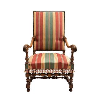 Sillón.  Francia.  Siglo XX.  Estilo Luis XIII.  En talla de madera de nogal.  Con respaldo cerrado y asiento en tapicería.