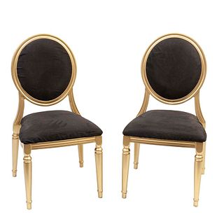 Lote de 2 sillas México. Siglo XX. Elaboradas en metal dorado. Con asientos de tapicería de tela blanca, respaldos ovalados.