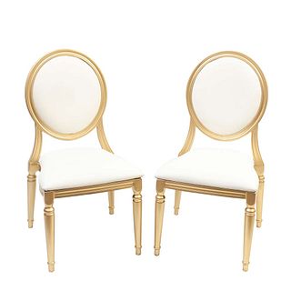 Lote de 2 sillas México. Siglo XX. Elaboradas en metal dorado. Con asientos de tapicería de tela blanca, respaldos ovalados y so...