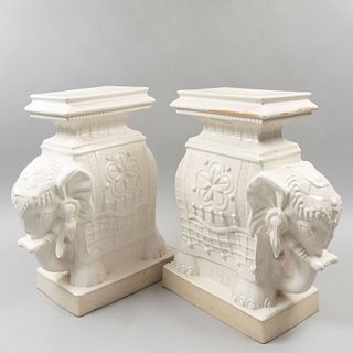 Par de pedestales. Siglo XX. Elaborados en cerámica. Con cubierta rectangular y fustes a manera de elefantes. 52 cm altura