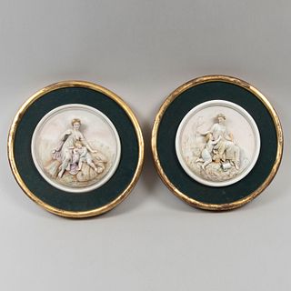Lote de 2 medallones en alto relieve. Siglo XX. Elaborados en porcelana. Acabado gres. Decorados con escenas neoclásicas.