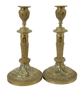 Pair of Louis XVI Style Gilt Candlesticks, foliate cast stem on round foot, with beaded border, height 11 inches. The Estate of Gloria Schiff, 630 Par
