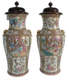Pair of Rose Medallion Vases having painted panels with gilt foo dog handles and wood carved covers, height 17 inches.