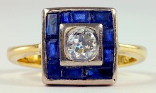 A SAPPHIRE AND DIAMOND CLUSTER RING, THE ROUND BRILLIANT CUT DIAMOND IN A SQUARE SURROUND OF CALIBRE