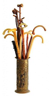 MISCELLANEOUS WOODEN WALKING STICKS AND CANES IN AN EMBOSSED BRASS STICK STAND
