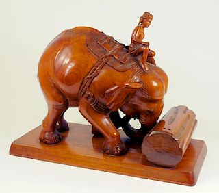 AN INDIAN CARVED WOOD SCULPTURE OF AN ELEPHANT PUSHING A LOG