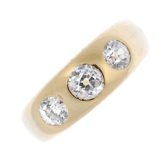 A late 19th century 18ct gold diamond three-stone ring. The slightly graduated old-cut diamond line,
