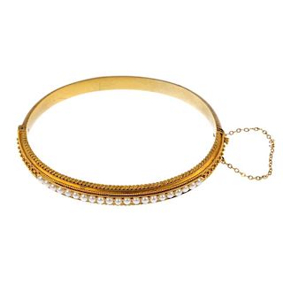 A late 19th century gold split pearl hinged bangle. The split pearl line, to the bead accent sides a