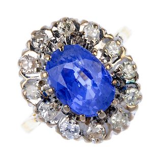 A mid 20th century 18ct gold sapphire and diamond cluster ring. The oval-shape sapphire, within a va