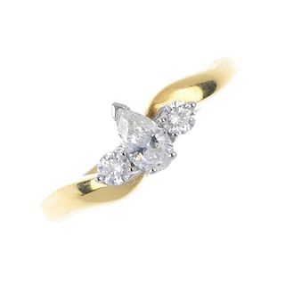 An 18ct gold diamond three-stone ring. The pear-shape diamond, to the brilliant-cut diamond asymmetr