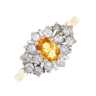 An 18ct gold sapphire and diamond cluster ring. The oval-shape orange sapphire, within an alternatin