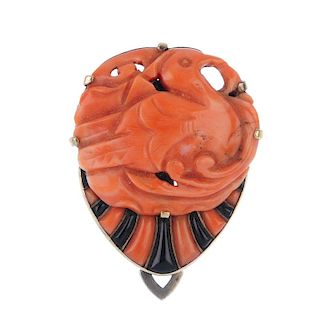A 1920s Art Deco coral and onyx clip. The carved coral bird and scrolling surround, above an alterna