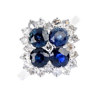 An 18ct gold sapphire and diamond cluster ring. The single-cut diamond, within a circular-shape sapp