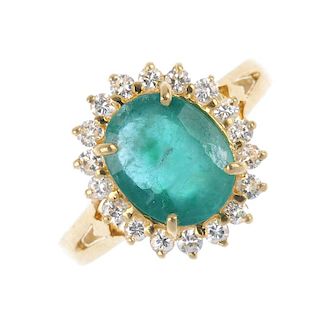 An emerald and diamond cluster ring. The oval-shape emerald, within a brilliant-cut diamond surround