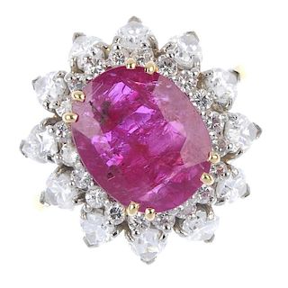 A ruby and diamond floral cluster ring. The oval-shape ruby, within a brilliant-cut diamond surround