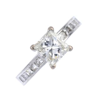 An 18ct gold diamond single-stone ring. The square-shape diamond, between similarly-cut diamond chan