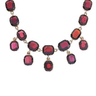 A garnet fringe necklace. Designed as a series of five suspended oval-shape garnet collet drops, to