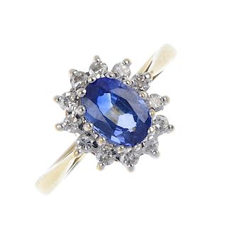 An 18ct gold sapphire and diamond cluster ring. The oval-shape sapphire, within a brilliant-cut diam
