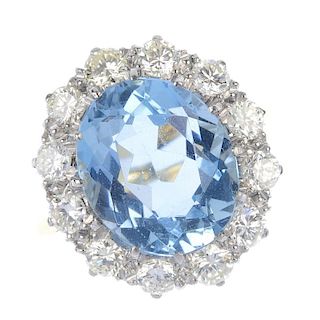An aquamarine and diamond cluster ring. The oval-shape aquamarine, within a brilliant-cut diamond su