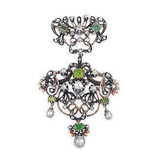 A foil-back diamond and emerald brooch. Of openwork design, the foil-back diamond and emerald scroll