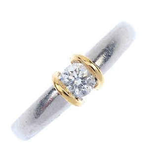 A platinum diamond single-stone ring. Of bi-colour design, the brilliant-cut diamond, with raised si