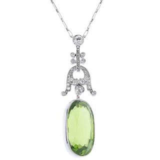 A peridot and diamond pendant. The oval-shape peridot collet, to the old and rose-cut diamond scroll