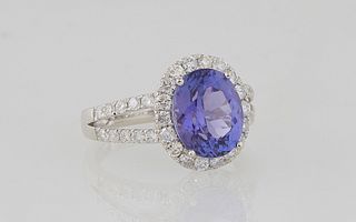 Lady's Platinum Dinner Ring, with an oval 3.75 ct. tanzanite, atop a border of round diamonds, the split shoulders of the band also mounted with round