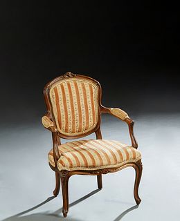 French Child's Louis XV Style Carved Walnut Fauteuil, early 20th c., the curved upholstered shield back with a floral carved crest rail, flanked by up