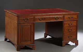 English Carved Mahogany Partner's Desk, early 20th c., the stepped rounded edge rectangular top with an inset red leather, over four frieze drawers on