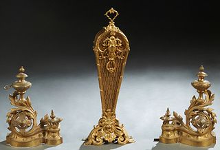 Three Brass Fireplace Items, 20th c., consisting of a pair of Louis XVI style gilt brass chenets with urn form tops issuing from pierced swirled leaf 