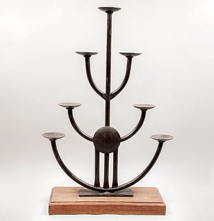 Portavelas. Siglo XX. Elaborado en hierro con base de madera. Diseño tubular con arandelas circulares.