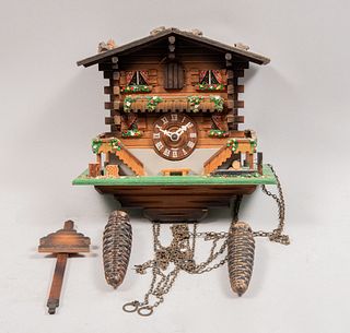 Reloj cucú. Alemania. Siglo XX. Diseño a manera de cabaña. En talla de madera policromada. Mecanismo de péndulo y contrapesos.