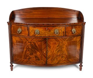 A Regency Carved and Figured Mahogany Satinwood Inlaid Bow-front Dresser
Height 38 1/4 x width 46 1/4 x depth 17 1/2 inches.