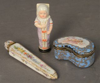 Three Porcelain Boxes, to include one in the form of a swaddled baby having a sterling silver cover; one small blue silver overlay box marked with cro