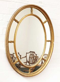 A George III-style oval wall mirror with mirrored slip,