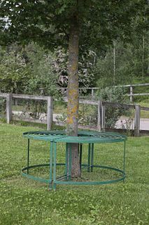 A Regency-style green-painted wrought iron tree seat,