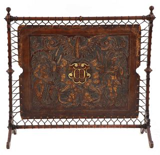 An embossed leather and walnut fire screen,